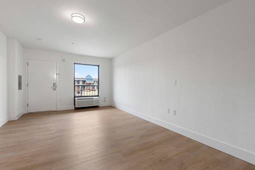 A large empty room with a view of a building outside the window.