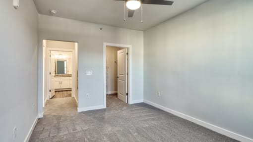 an empty living room with white walls and a ceiling fan at The Bella at Westchester, Midlothian, VA, 23113