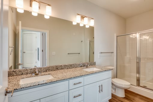 a bathroom with two sinks and a shower and a toilet at The Bella at Westchester, Virginia