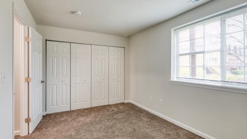 an empty bedroom with two closets and a window