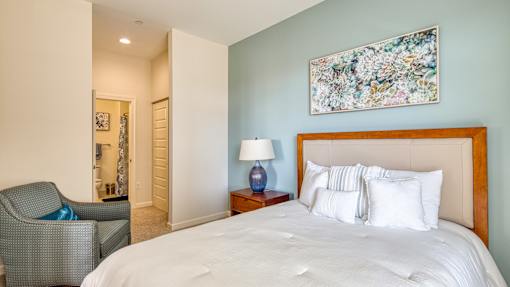 A bedroom with a large bed and a chair.
