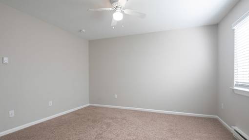 A room with a ceiling fan and carpeted floor.