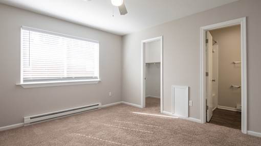 A room with a window, a door, and a carpeted floor.
