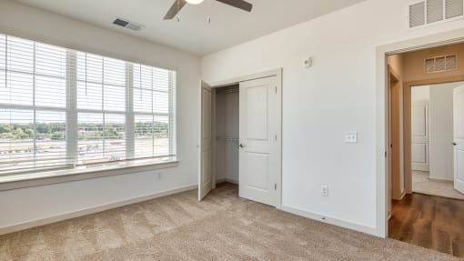 an empty bedroom with a large window and a door to a closet at The Walker Virginia Center, Virginia, 23059