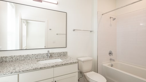 a bathroom with a white bathtub and a white sink with granite countertop at Ainsworth, Richmond, VA