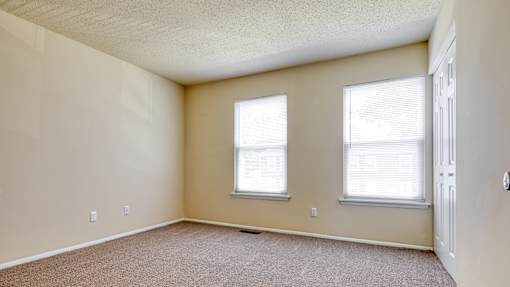 A room with two windows and a carpeted floor.