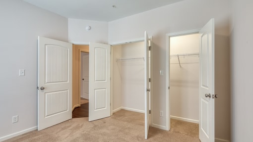an empty bedroom with three closets and three doors