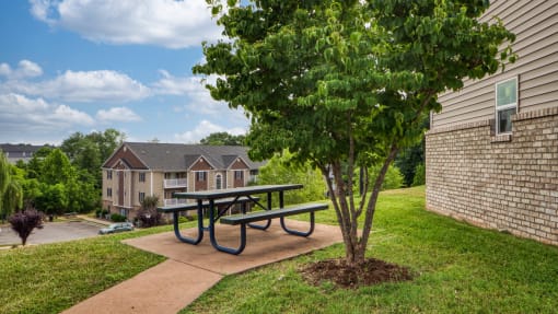 a picnic table with a tree in front of a building