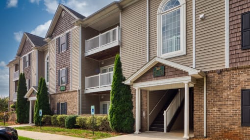 an apartment building with tan siding and a sidewalk