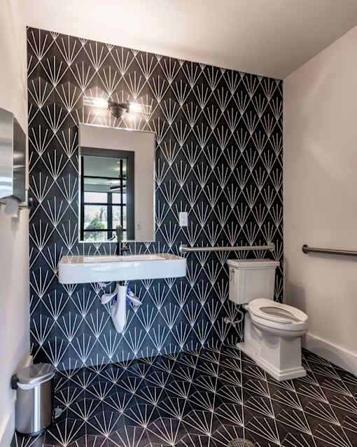 A bathroom with a black and white patterned wallpaper.