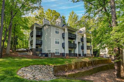 A large apartment building with a stone wall in front of it.