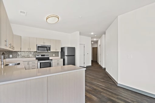 a white kitchen with a large island and a stainless steel refrigeratorat Metropolis Apartments, Virginia
