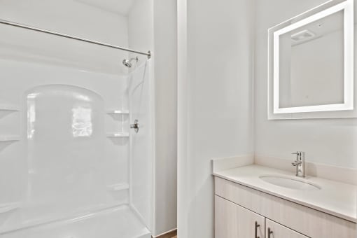a bathroom with a shower and a sink and a mirrorat Metropolis Apartments, Glen Allen, VA 