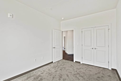 a bedroom with white walls and doors and a carpetat Metropolis Apartments, Virginia, 23060