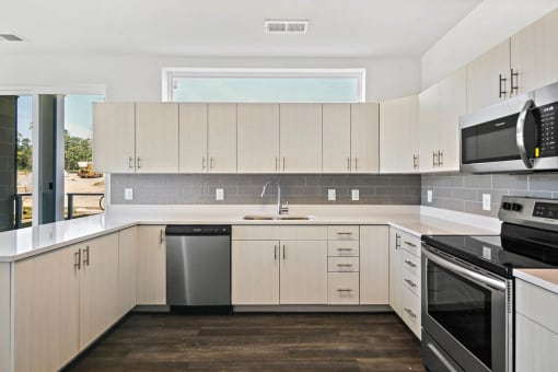 a kitchen with white cabinets and black appliances and a windowat Metropolis Apartments, Virginia, 23060