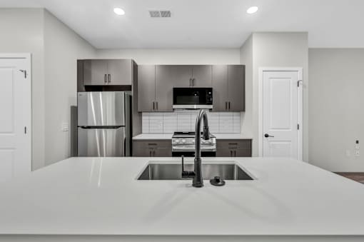 A modern kitchen with a stainless steel refrigerator and a white countertop.