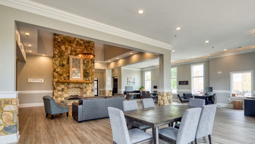 the gathering room has a large stone fireplace and a table with chairs
