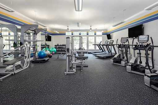 A spacious gym with various exercise equipment and a blue exercise ball.