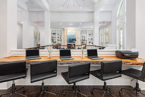 A room with a long table and chairs with laptops on it.