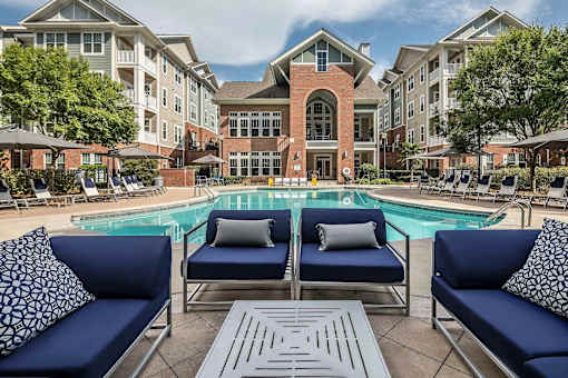 A pool area with blue couches and a brick building in the background.