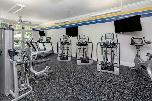 A gym with a variety of equipment including treadmills, stationary bikes, and weight machines.