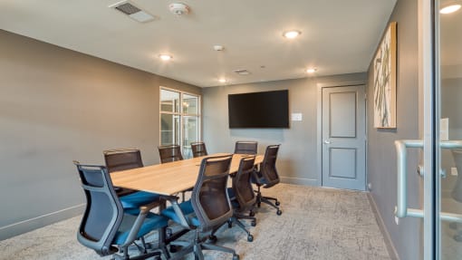 a conference room with a wooden table and chairs and a wall mounted tv at The Bella at Westchester, Midlothian, 23113