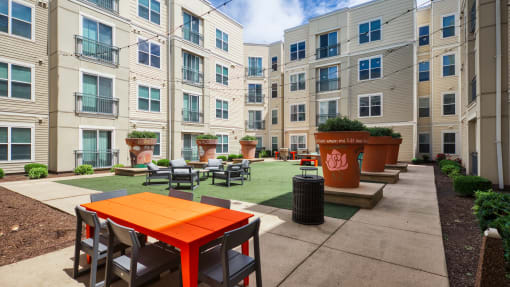 an outdoor patio with tables and chairs in front of an apartment building at Proximity at ODU, Norfolk