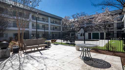 A courtyard with a bench and a table surrounded by a fence.
