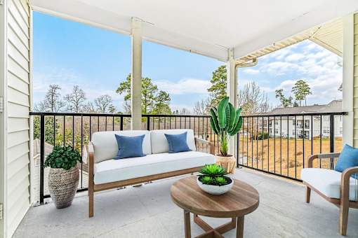 A white sofa with blue pillows sits on a patio with a wooden coffee table in front of it.