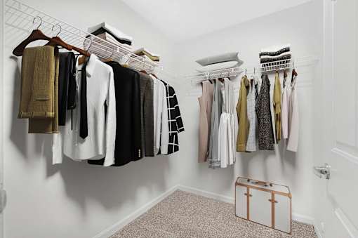 A white closet with clothes hanging on hangers.