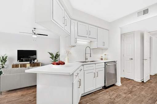 A white kitchen with a large island and a ceiling fan.