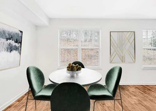 A white table with a bowl of fruit on it and four green chairs.