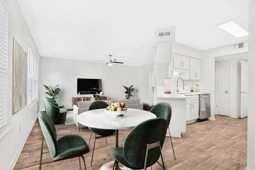 A white dining table surrounded by green chairs in a white room.