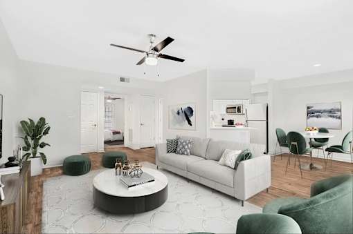 A living room with a white couch, a coffee table, and a ceiling fan.