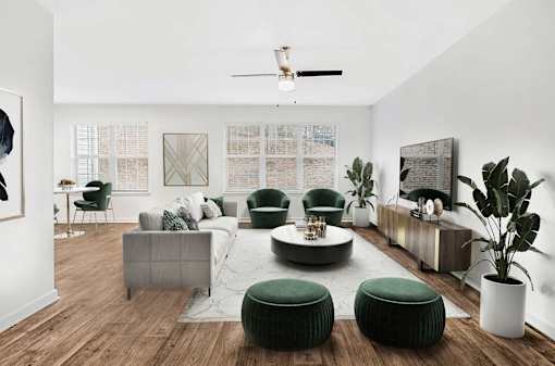 A living room with a grey sofa, green ottoman, and a wooden floor.