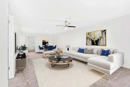 A living room with a white couch, a coffee table, and a painting on the wall.