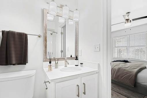 A white bathroom with a brown towel hanging on the tub.
