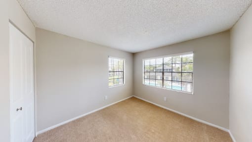 a bedroom with two windows and a door