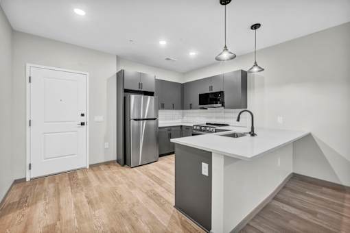 A modern kitchen with a white countertop and stainless steel appliances.