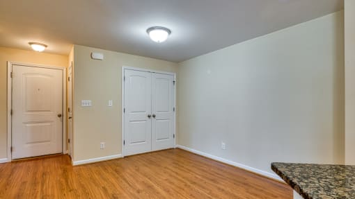 an empty living room with wood flooring and white doors