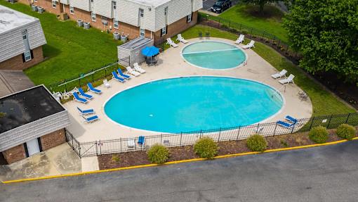 An aerial view of a pool with a blue fence and chairs around it.