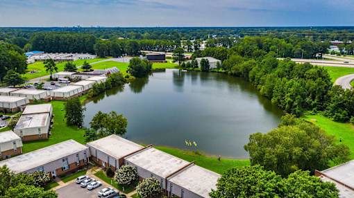 A serene landscape with a lake, greenery, and a building complex.