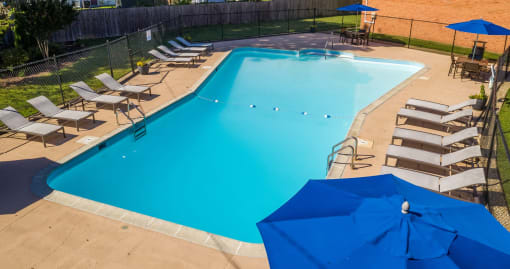 a swimming pool with chairs and umbrellas around it