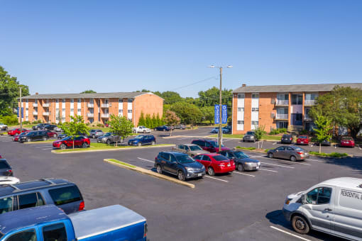 a parking lot with cars in front of an apartment building