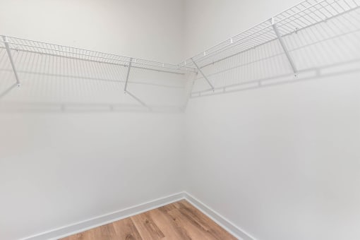 the closet in a bedroom with white walls and a wood floor