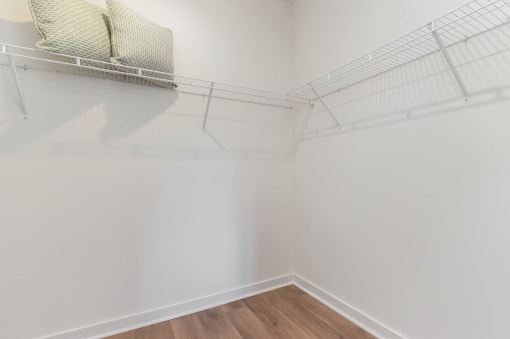 a closet in a room with white walls and a wood floor