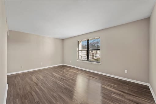 a bedroom with hardwood floors and a window