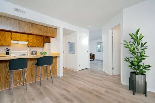 A kitchen with wooden cabinets and a bar area with two stools.