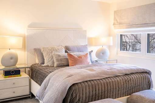 A bedroom with a bed, nightstands, and lamps.