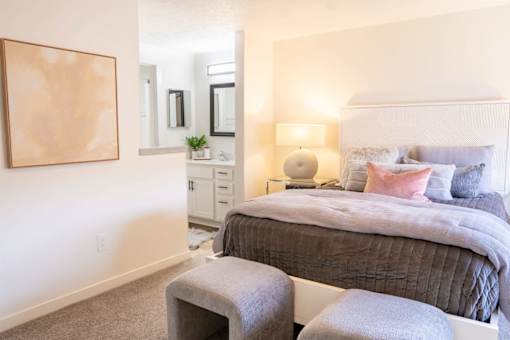 A bedroom with a large bed and a grey ottoman.